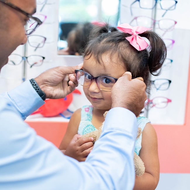 Young child putting on eyeglasses at Family Vision Optical