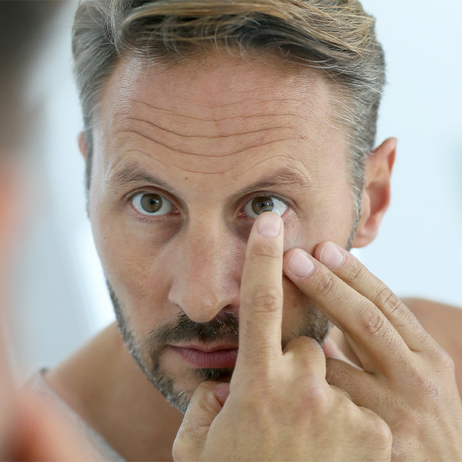 Man putting on contact lens at Family Vision Optical