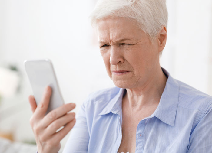 Woman squinting while looking at her phone